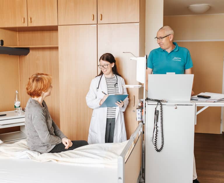 887A1334-Bearbeitet Eine Patientin sitzt entspannt auf einem Bett während der Arztvisite.